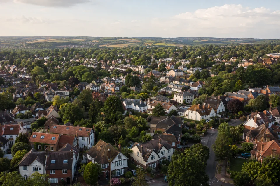 Aerial view of a leafy UK residential neighbourhood and surrounding countryside.